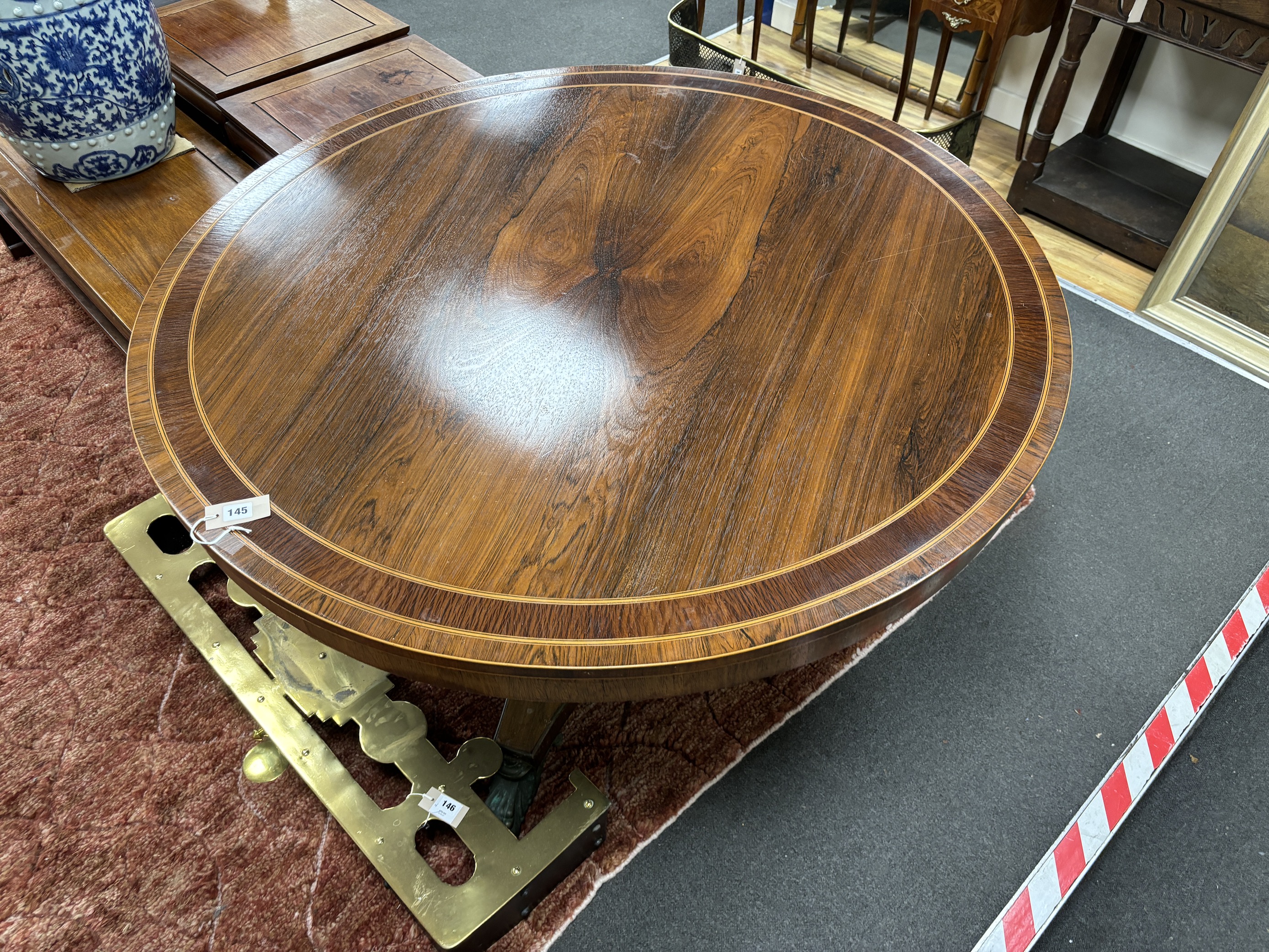 A Regency circular banded rosewood tilt top breakfast table on ormolu claw feet, diameter 132cm, height 73cm